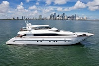 a white motor yacht in the water with a city in the background
